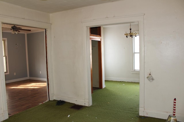 interior space with ceiling fan with notable chandelier, baseboards, and carpet floors