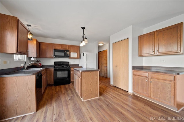 kitchen featuring dark countertops, black appliances, a sink, and wood finished floors