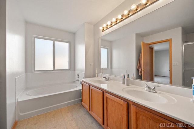 bathroom with a garden tub, double vanity, a sink, and tile patterned floors