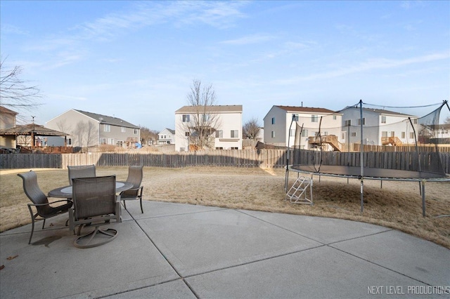 view of patio / terrace featuring a trampoline, a residential view, outdoor dining area, and a fenced backyard