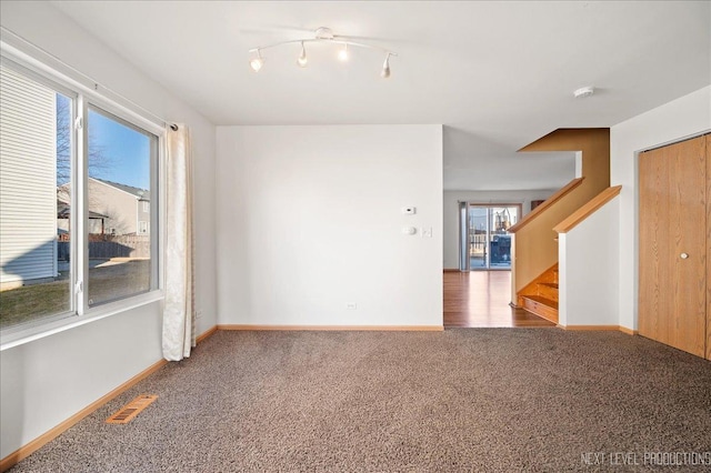 spare room with carpet floors, stairway, baseboards, and visible vents