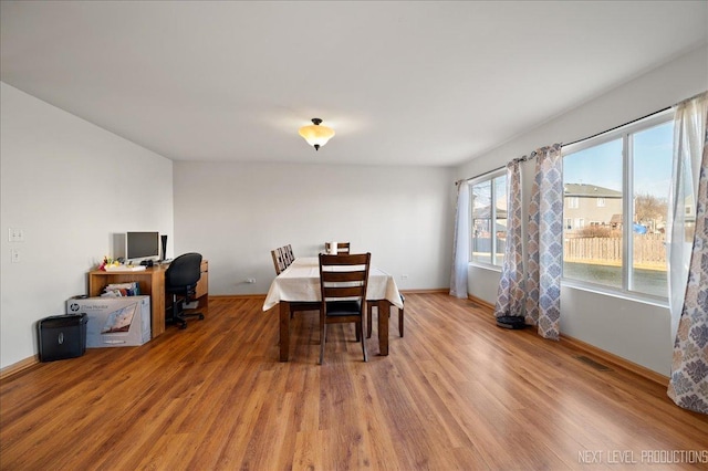 dining space featuring light wood finished floors, visible vents, and baseboards