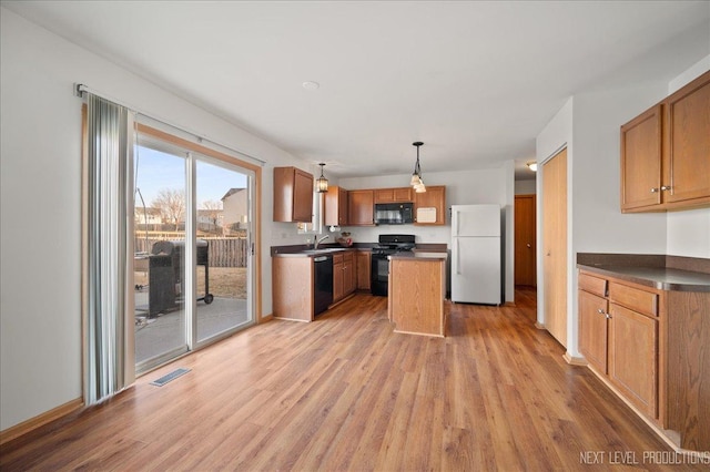 kitchen featuring visible vents, dark countertops, light wood-type flooring, black appliances, and a sink