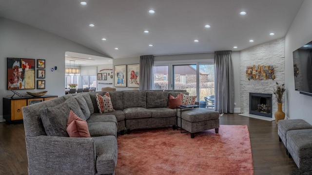 living area with a wealth of natural light, a stone fireplace, and dark wood finished floors