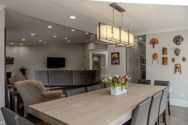 dining space with a stone fireplace, wood finished floors, recessed lighting, and baseboards