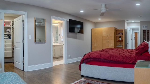 bedroom featuring a spacious closet, wood finished floors, visible vents, and baseboards