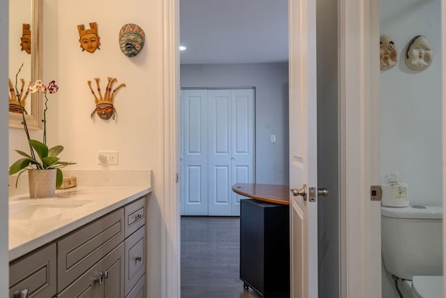 bathroom with toilet, wood finished floors, and vanity