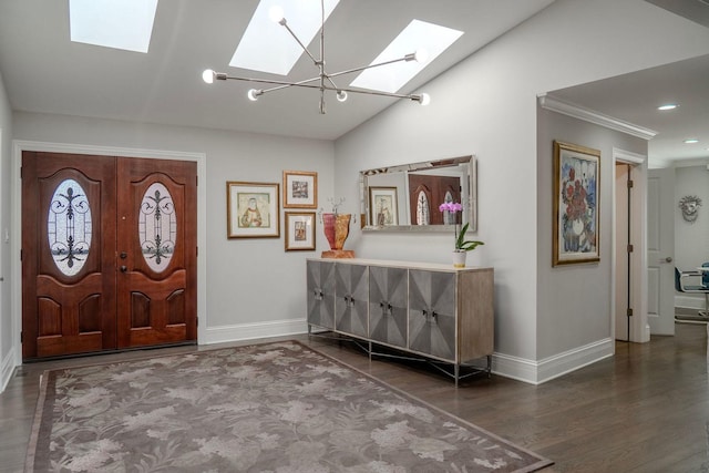 foyer with vaulted ceiling with skylight, wood finished floors, baseboards, and ornamental molding