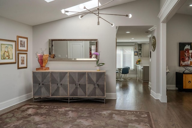 interior space featuring baseboards, vaulted ceiling with skylight, and wood finished floors