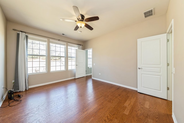 spare room with baseboards, wood finished floors, visible vents, and ceiling fan