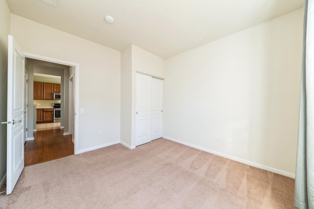 unfurnished bedroom with carpet, baseboards, and a closet