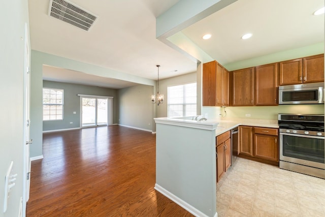 kitchen featuring visible vents, light countertops, brown cabinetry, a notable chandelier, and stainless steel appliances