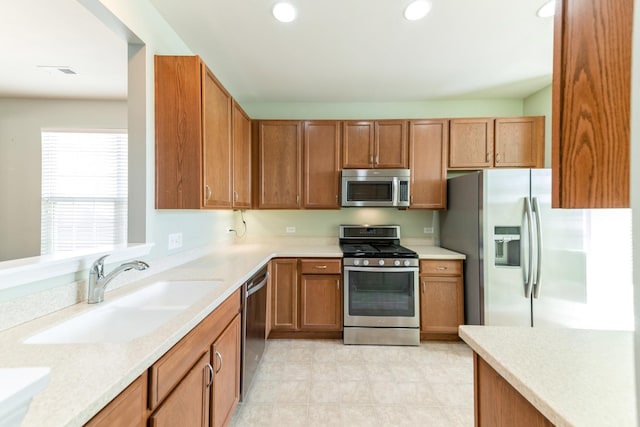 kitchen featuring brown cabinetry, recessed lighting, a sink, light countertops, and appliances with stainless steel finishes