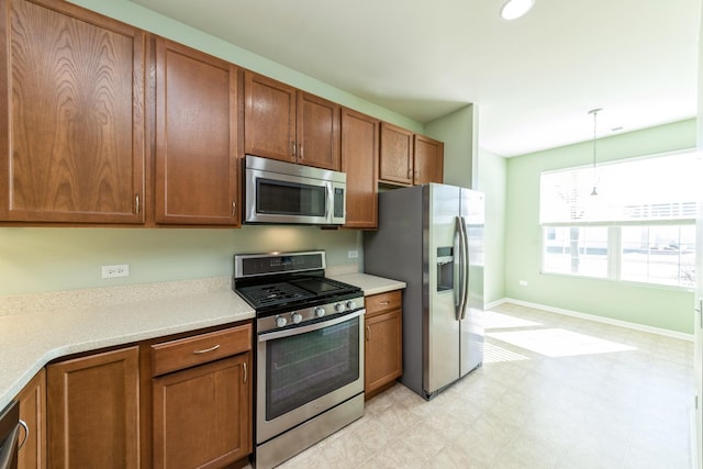 kitchen with decorative light fixtures, stainless steel appliances, brown cabinets, and light countertops