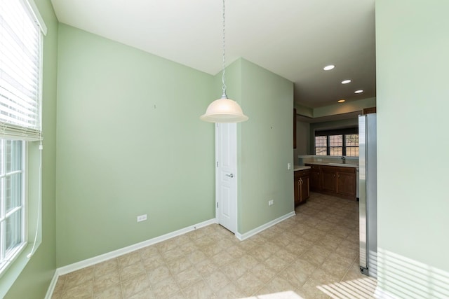 interior space featuring recessed lighting, baseboards, light floors, and a sink