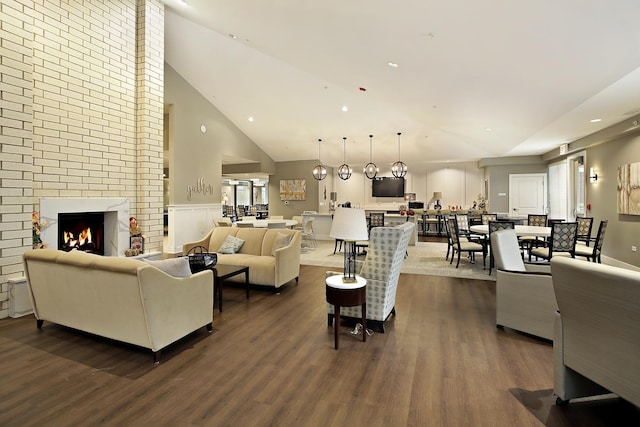 living area featuring dark wood finished floors, a brick fireplace, and high vaulted ceiling