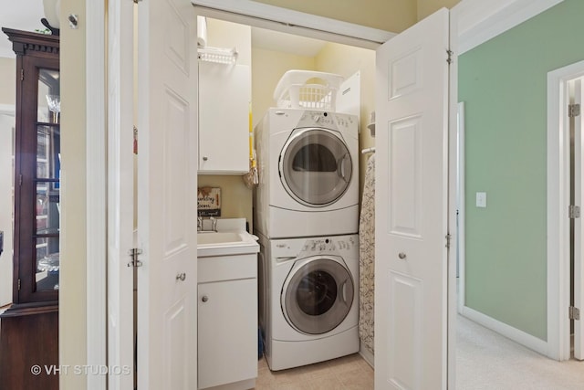 washroom featuring a sink, laundry area, light tile patterned floors, and stacked washing maching and dryer