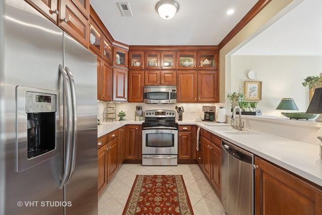 kitchen featuring visible vents, ornamental molding, light tile patterned floors, appliances with stainless steel finishes, and a sink