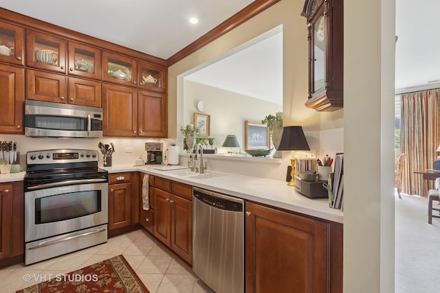 kitchen with a sink, stainless steel appliances, light tile patterned flooring, crown molding, and light countertops