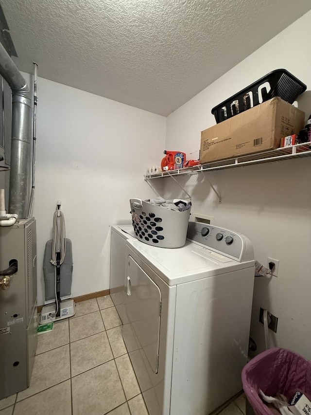 laundry room featuring light tile patterned floors, washing machine and dryer, a textured ceiling, laundry area, and baseboards