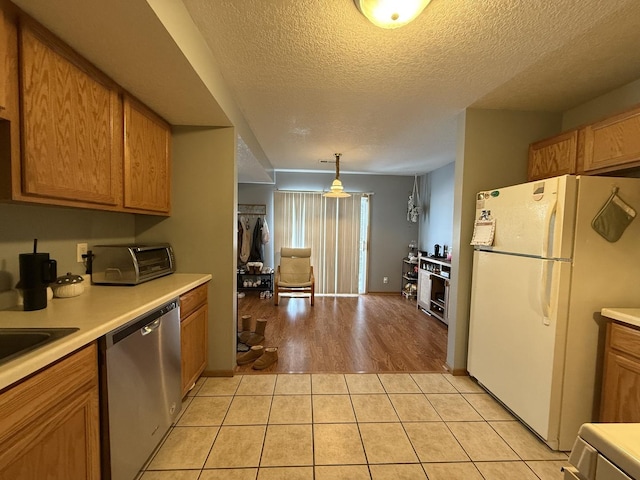 kitchen featuring light tile patterned flooring, light countertops, dishwasher, and freestanding refrigerator