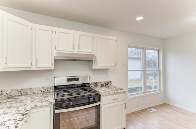 kitchen featuring visible vents, white cabinetry, gas range, under cabinet range hood, and baseboards