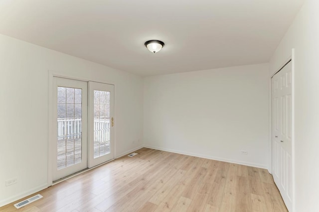 unfurnished room with visible vents, light wood-style flooring, and baseboards