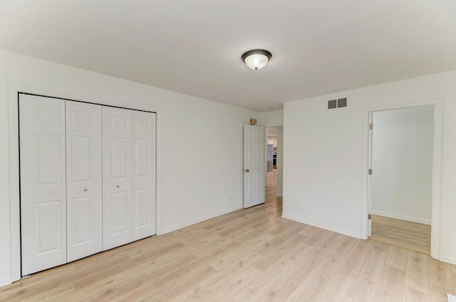 unfurnished bedroom with light wood-style flooring, a closet, visible vents, and baseboards