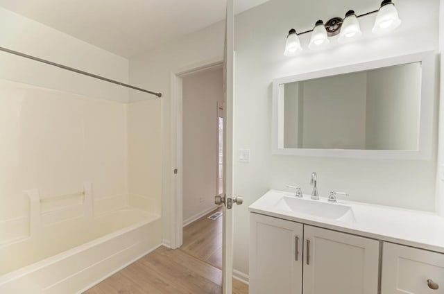 full bath with bathtub / shower combination, vanity, and wood finished floors