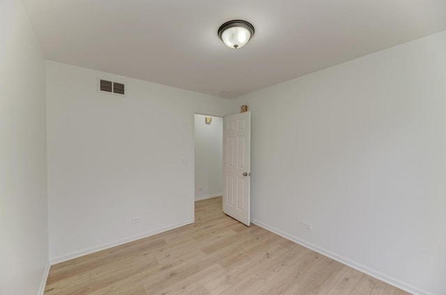 spare room with light wood-style flooring, visible vents, and baseboards