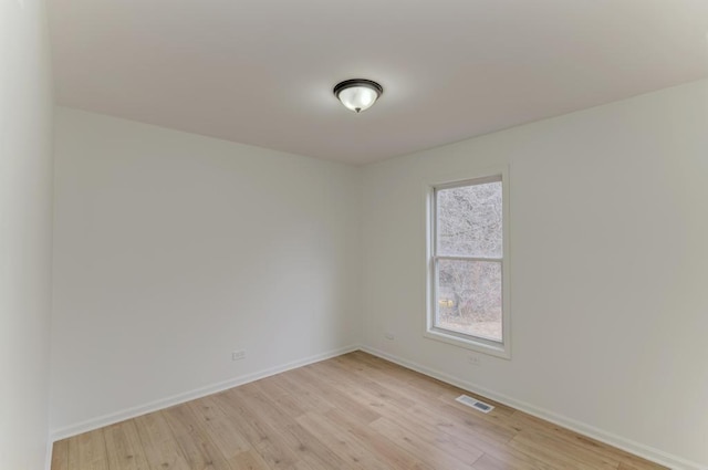 empty room featuring baseboards, visible vents, and light wood finished floors