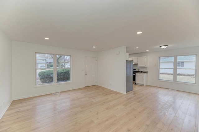 unfurnished living room with light wood-style floors, a wealth of natural light, and recessed lighting