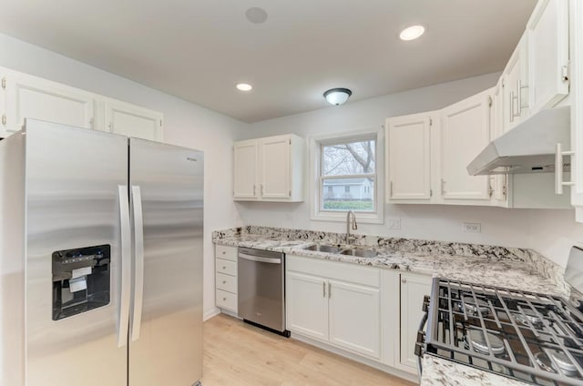 kitchen with white cabinets, light wood-style flooring, stainless steel appliances, a sink, and recessed lighting