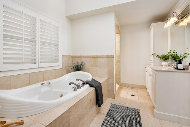 bathroom with tile patterned flooring, a tub with jets, walk in shower, and vanity