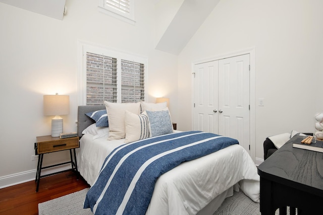 bedroom featuring high vaulted ceiling, a closet, baseboards, and wood finished floors