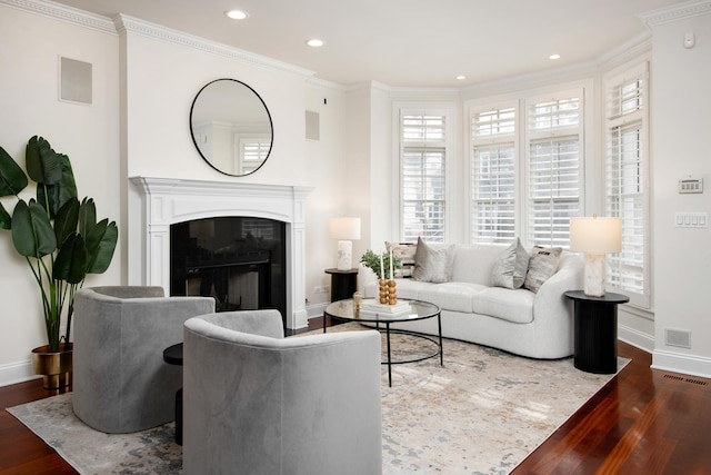 living area with ornamental molding, a fireplace, wood finished floors, and visible vents