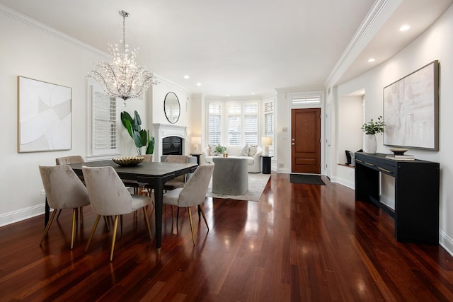 dining room with baseboards, ornamental molding, dark wood-type flooring, and a glass covered fireplace