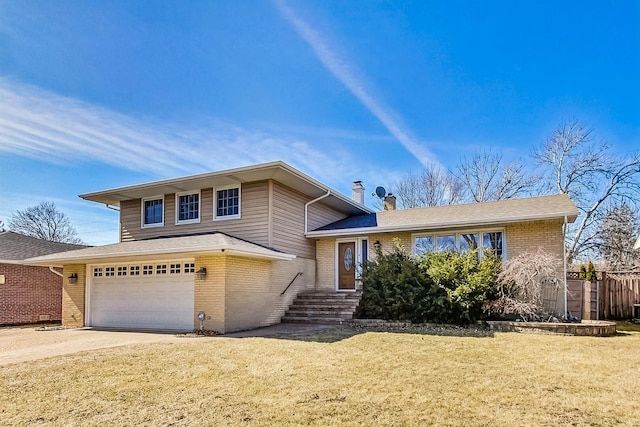 split level home with brick siding, a chimney, concrete driveway, a front yard, and fence