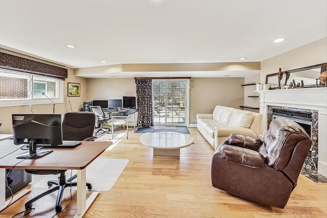 living room with light wood-type flooring, baseboards, recessed lighting, and a premium fireplace