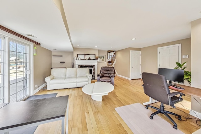 office area featuring light wood-style floors, a brick fireplace, visible vents, and recessed lighting