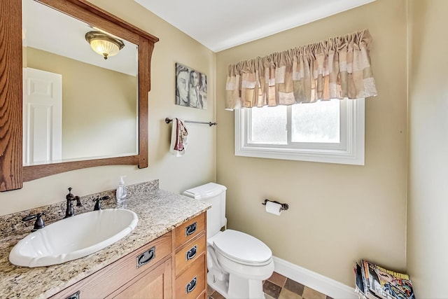 bathroom with vanity, toilet, and baseboards