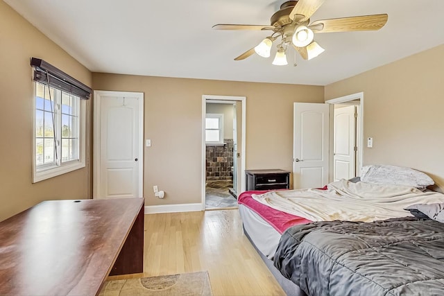 bedroom featuring ceiling fan, light wood-style flooring, baseboards, and ensuite bath