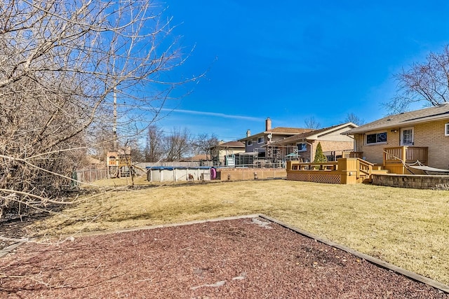 view of yard with a deck, fence, a residential view, and a covered pool