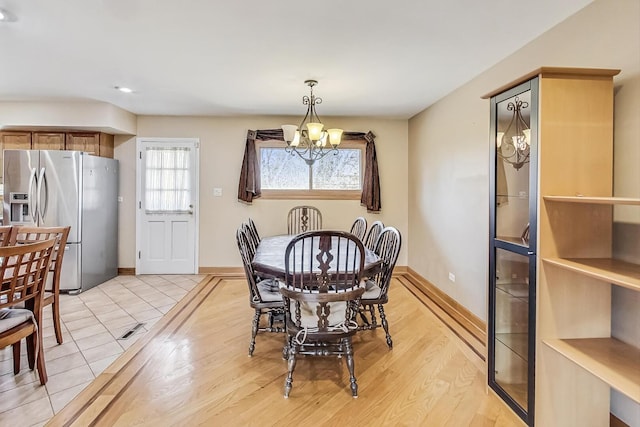 dining space with light wood finished floors, baseboards, and a chandelier