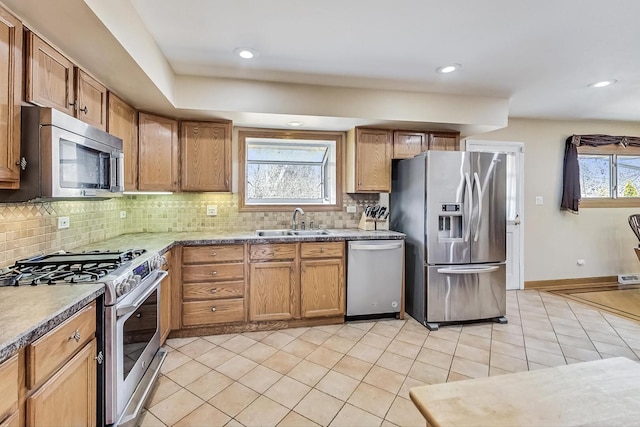 kitchen with light tile patterned floors, tasteful backsplash, baseboards, stainless steel appliances, and a sink