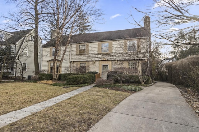 view of front of property with stone siding, a chimney, and a front lawn