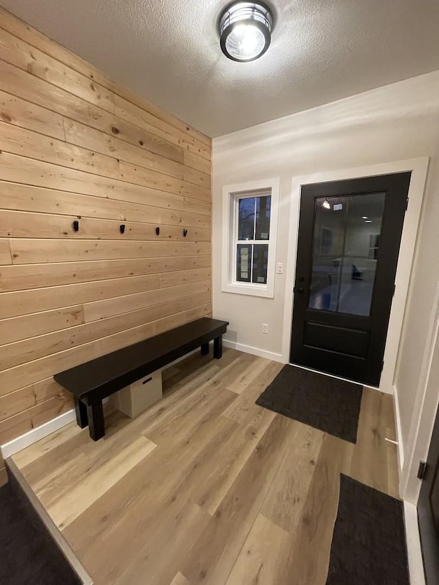 entrance foyer with a textured ceiling, wood finished floors, and wooden walls