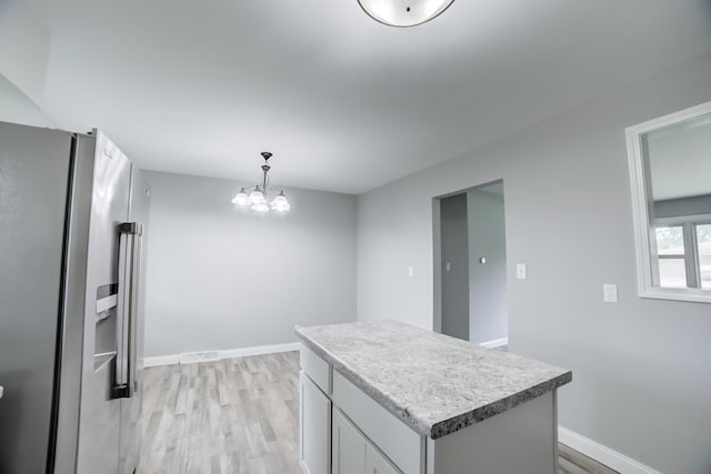 1978 Fleming St, Watseka, IL 60970 - kitchen with stainless steel refrigerator with ice dispenser, light wood finished floors, a chandelier, light countertops, and baseboards