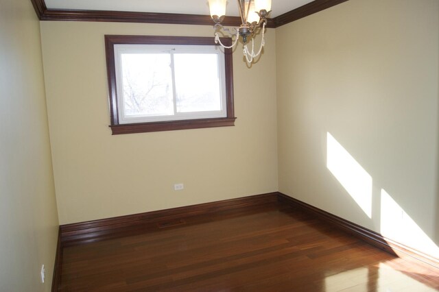 unfurnished room featuring ornamental molding, dark wood finished floors, baseboards, and an inviting chandelier