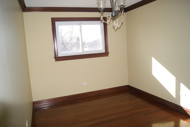 empty room with an inviting chandelier, baseboards, wood finished floors, and ornamental molding